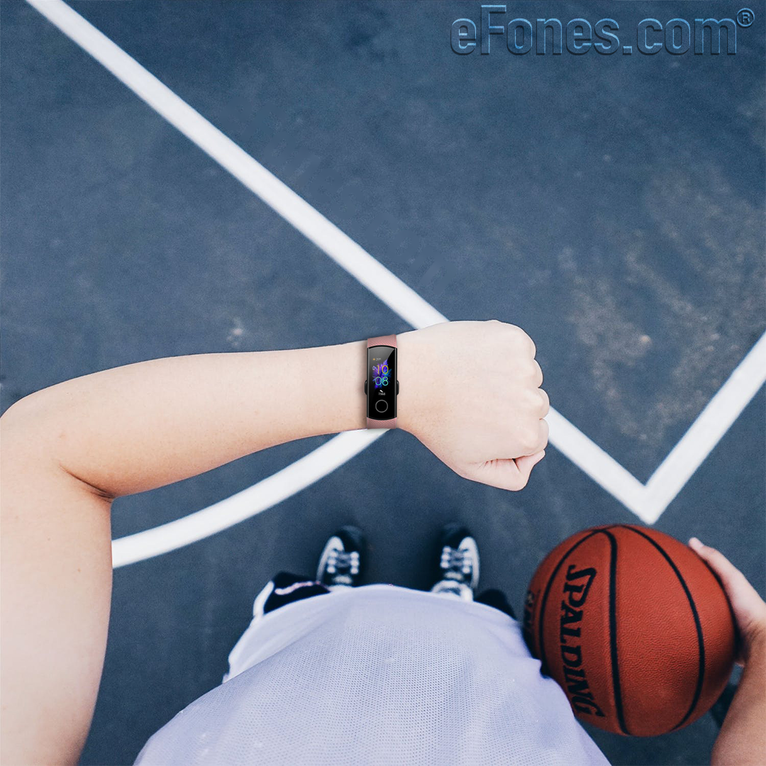 Person holding a Spalding basketball on an outdoor court wearing a fitness tracker smartwatch
