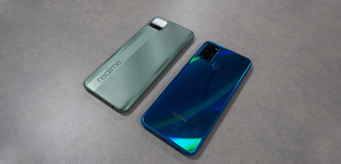 Back view of green realme C11 and blue Honor 9A smartphones on gray surface
