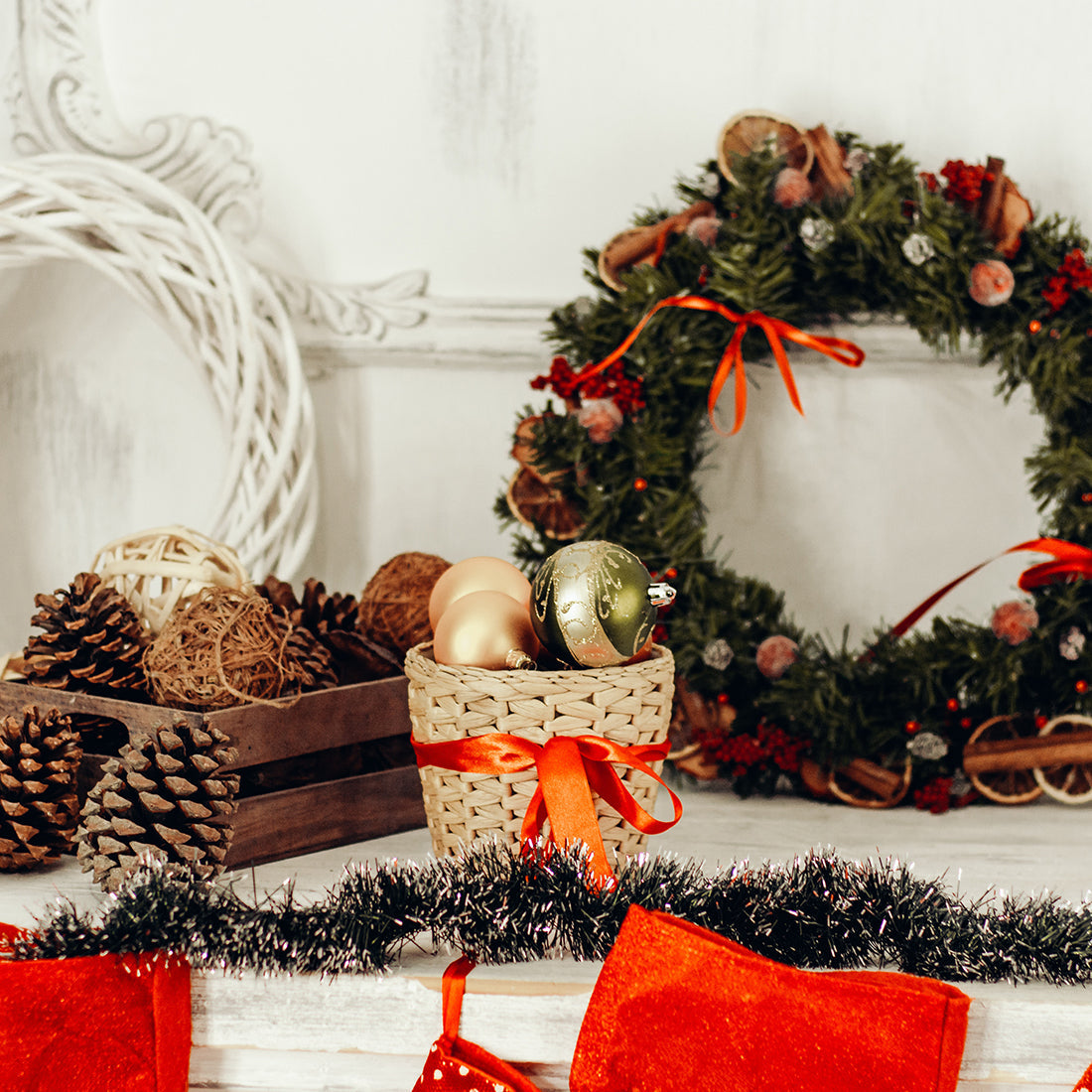 Christmas decor with pine cones, woven basket with baubles, festive wreath, and red stockings